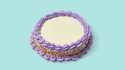 Colorful birthday cake with purple frosting and white flowers on a blue background.