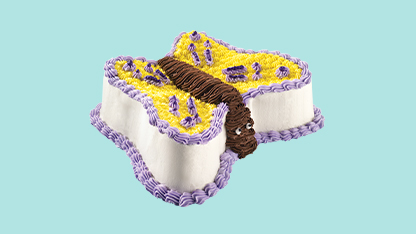 Cake designed to look like a birthday card, with yellow icing and purple flowers, on a blue background.