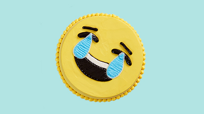 A smiley face cake decorated like a coin and labeled as "SMILEY FACE COIN" with a blue background.